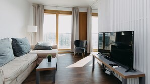 A modern living room with a sofa, a coffee table, a TV, and a chair. - ShortStayPoland Kolejowa - B10 (Warsaw)