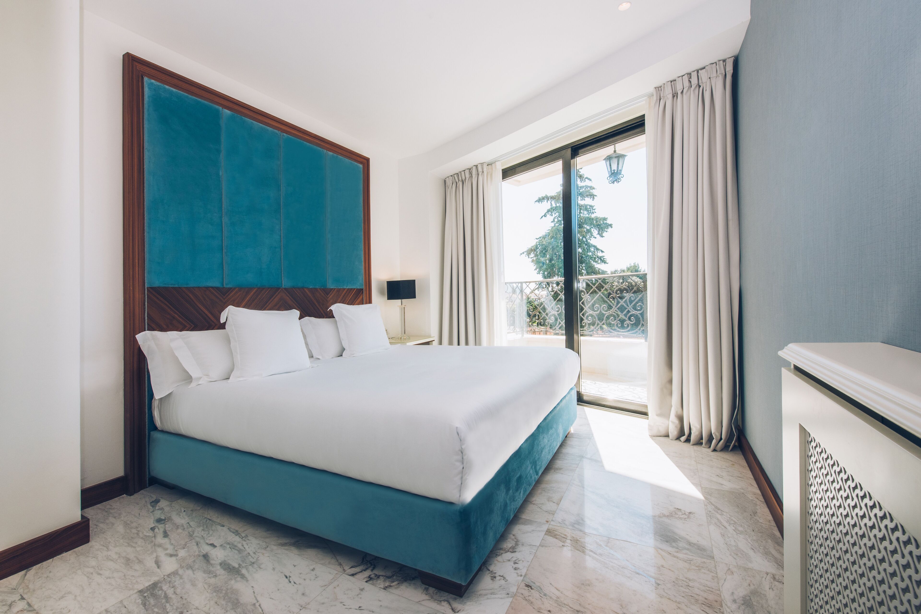 Habitación de hotel con una cama grande, vistas al exterior y un balcón.
