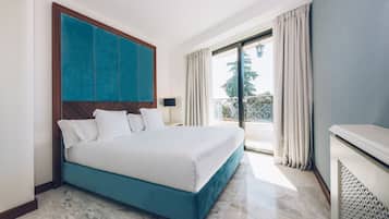 Habitación de hotel con una cama grande, vistas al exterior y un balcón.