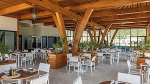 Un espace extérieur aménagé pour les repas, avec des poutres en bois, du mobilier blanc et des plantes en pot.