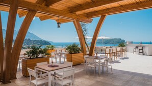 Une terrasse extérieure avec des poutres en bois, des tables et des chaises blanches, et des plantes en pot.