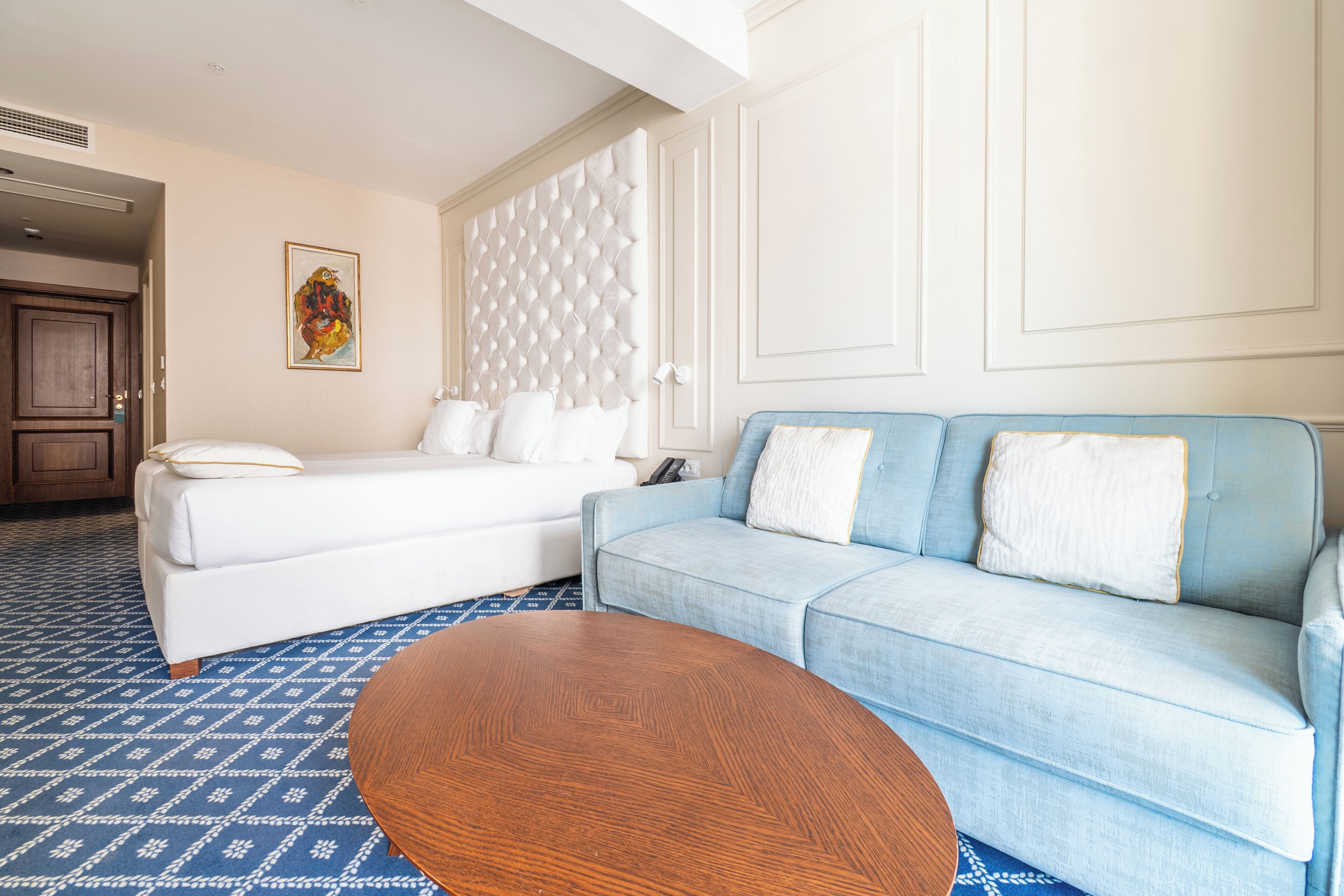 Ein Hotelzimmer mit einem Bett, einem blauen Sofa und einem Holztisch.