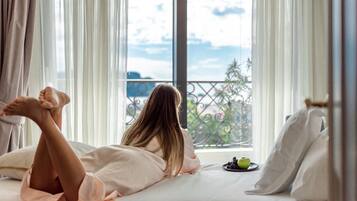 Una persona recostada en una cama con vistas a un balcón y una manzana verde sobre la mesita de noche.