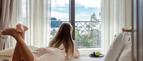 A person lying on a bed with a view of a balcony and a green apple on the bedside table.