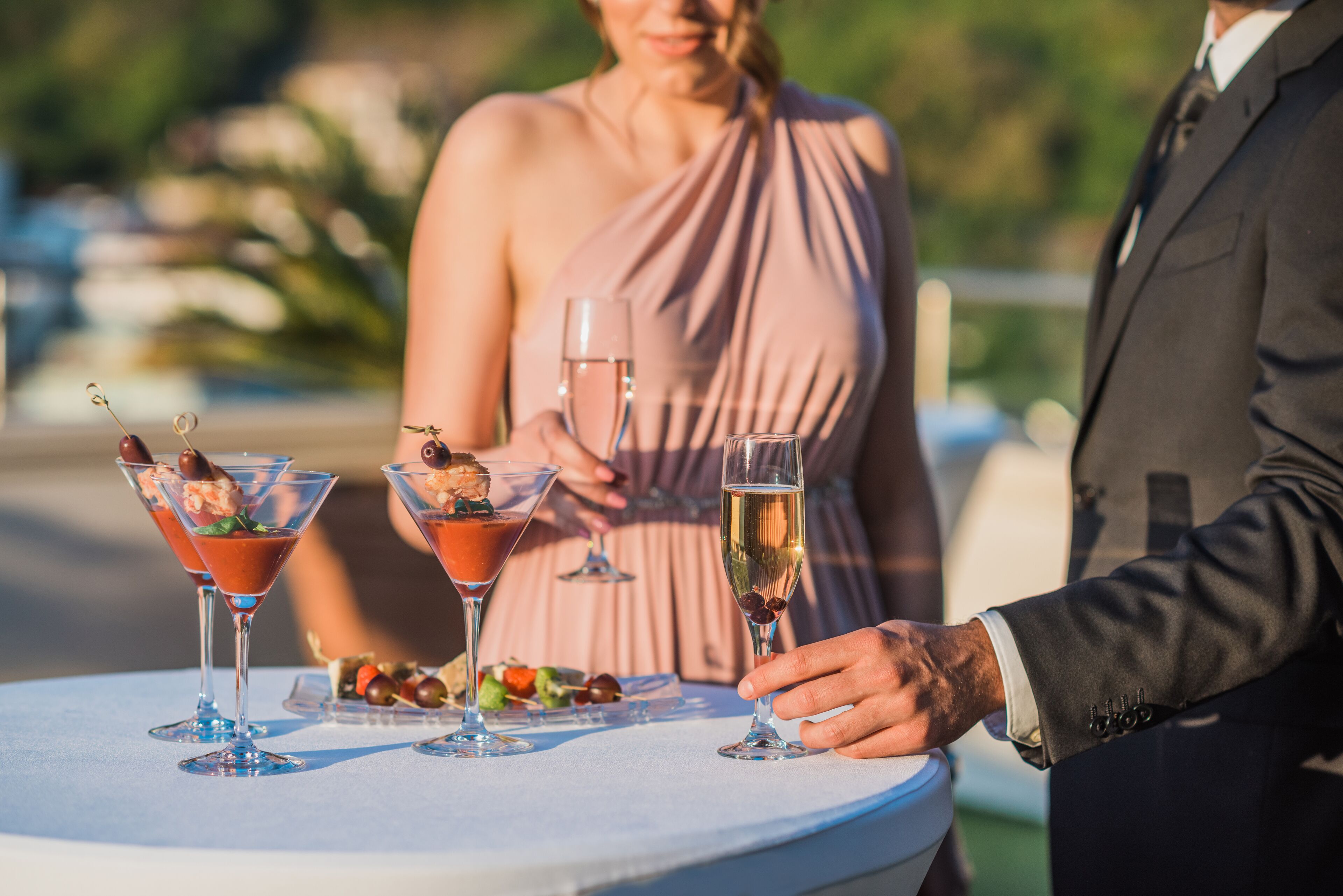 A table with three martini glasses, a plate of food, and a person in a suit.