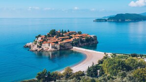 Un village côtier aux bâtiments aux toits de tuiles rouges, avec une plage et une vue dégagée sur la mer.