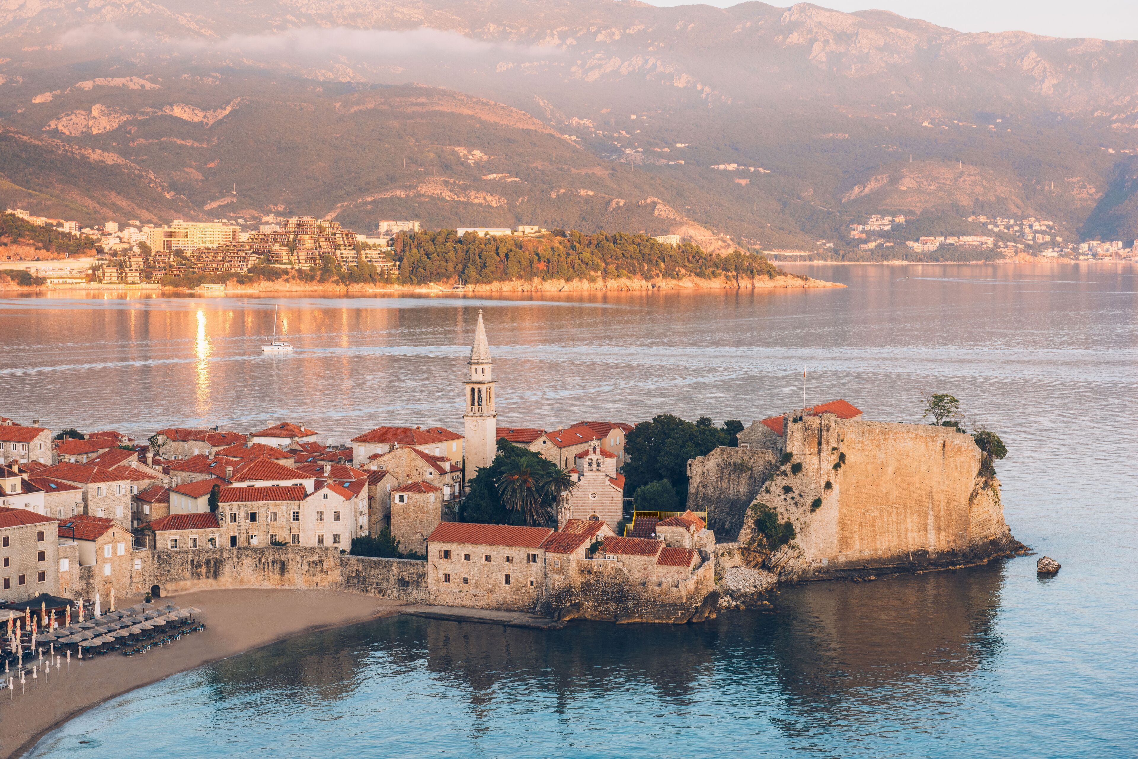 A coastal town with a prominent castle and a church with a bell tower.