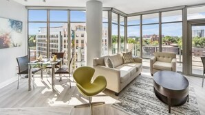 Un salon moderne avec de grandes fenêtres, une table à manger en verre, un canapé et une table basse.