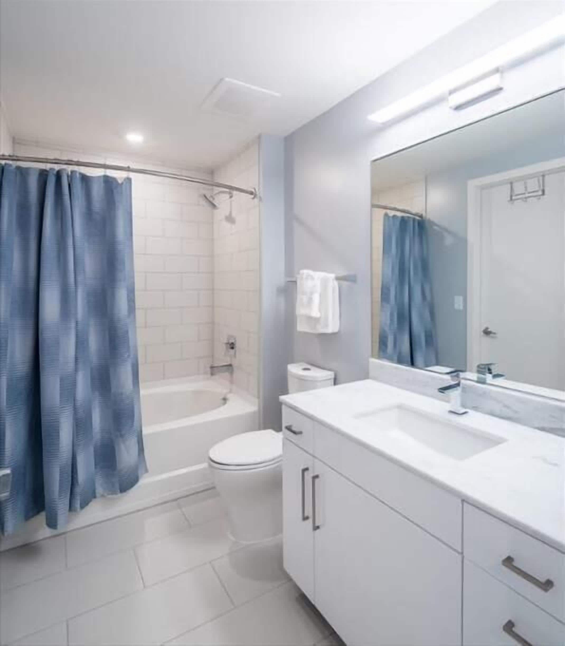 A modern bathroom with a white sink, mirror, and cabinet.
