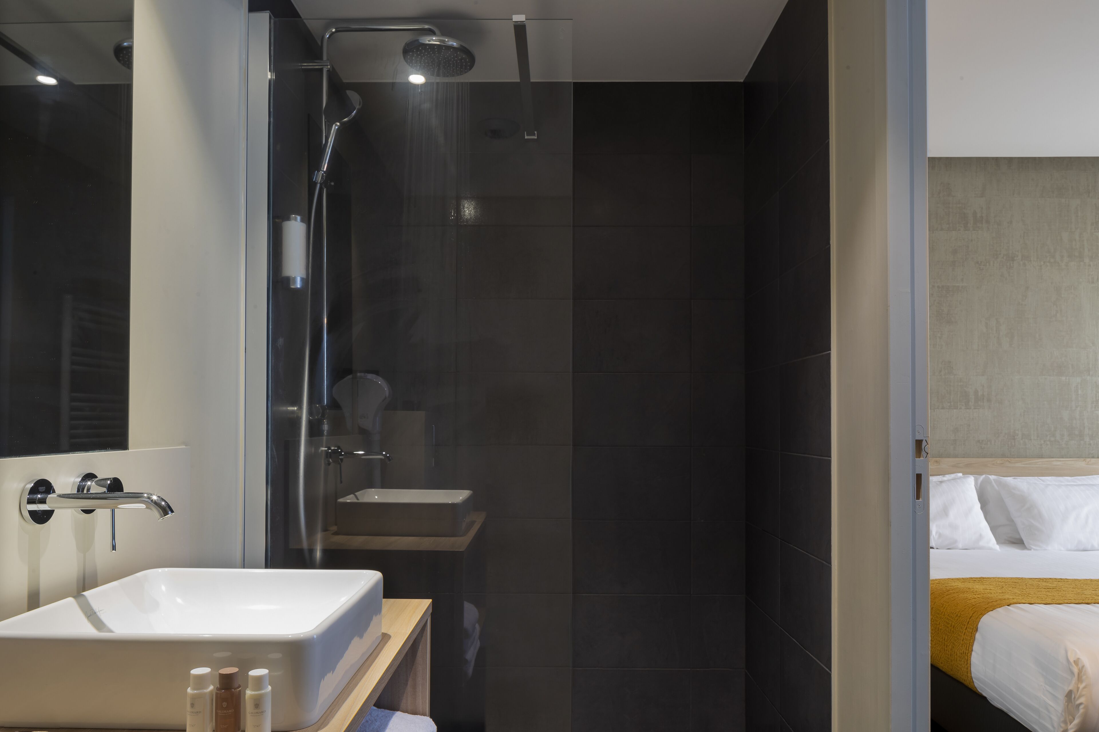 A modern bathroom with a large sink, shower, and toilet.