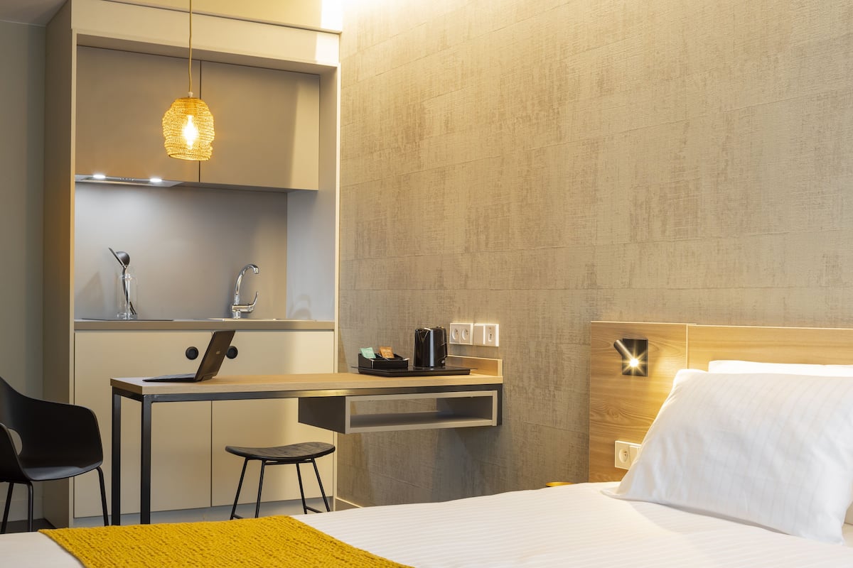 Ein modernes Hotelzimmer mit Bett, Schreibtisch, Stuhl und einer Pendelleuchte.