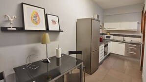 Une cuisine compacte équipée d’un réfrigérateur, d’un four à micro-ondes et d’une cuisinière. On y trouve une table à manger avec une lampe et un tableau encadré au mur.