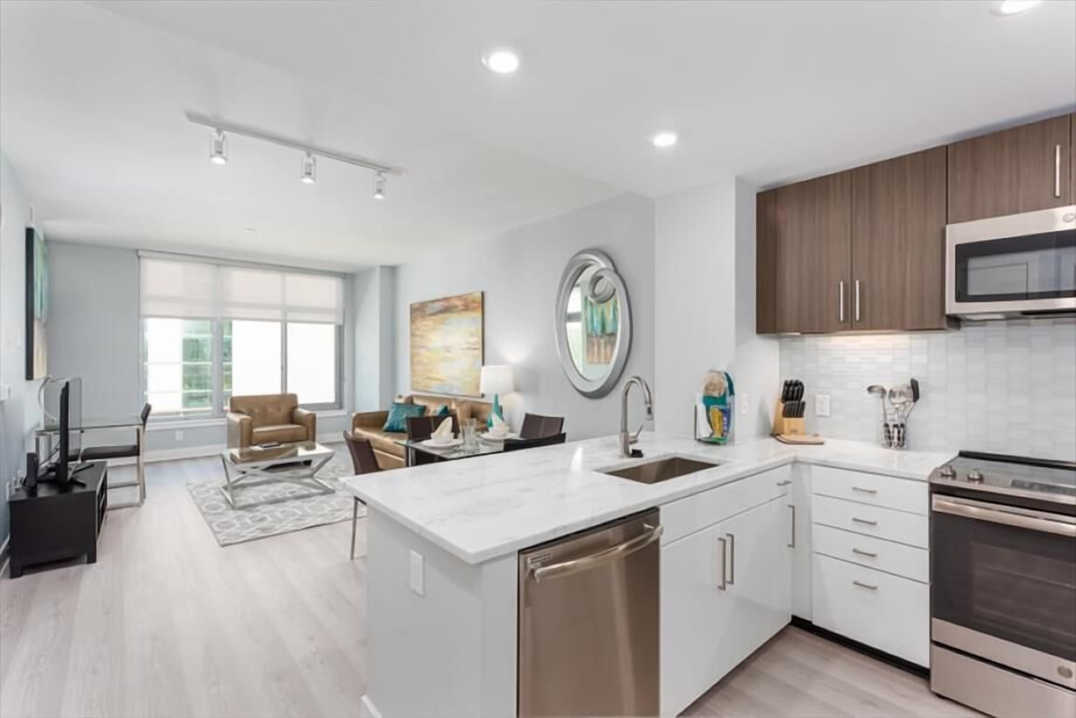 A modern kitchen with white cabinetry, stainless steel appliances, and a large island with a sink.