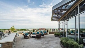 Une terrasse sur le toit, aménagée avec du mobilier d’extérieur, un barbecue et offrant une vue sur le paysage urbain.