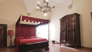 A bedroom with a four-poster bed, a wooden wardrobe, and a chandelier.