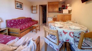A compact room with a bed, a dining table with chairs, a small kitchenette, and a television. - 5th floor, tv, ski locker, 22m², Les Menuires (Les Menuires)