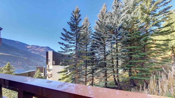 A balcony with a view of a mountain, trees, and a building. - 5th floor, tv, ski locker, 22m², Les Menuires (Les Menuires)