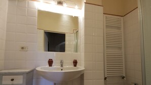 Une salle de bain avec un lavabo blanc, un miroir et une petite commode.