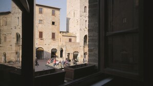Une vue d’une cour intérieure avec des bâtiments en pierre et quelques personnes assises sur des bancs.