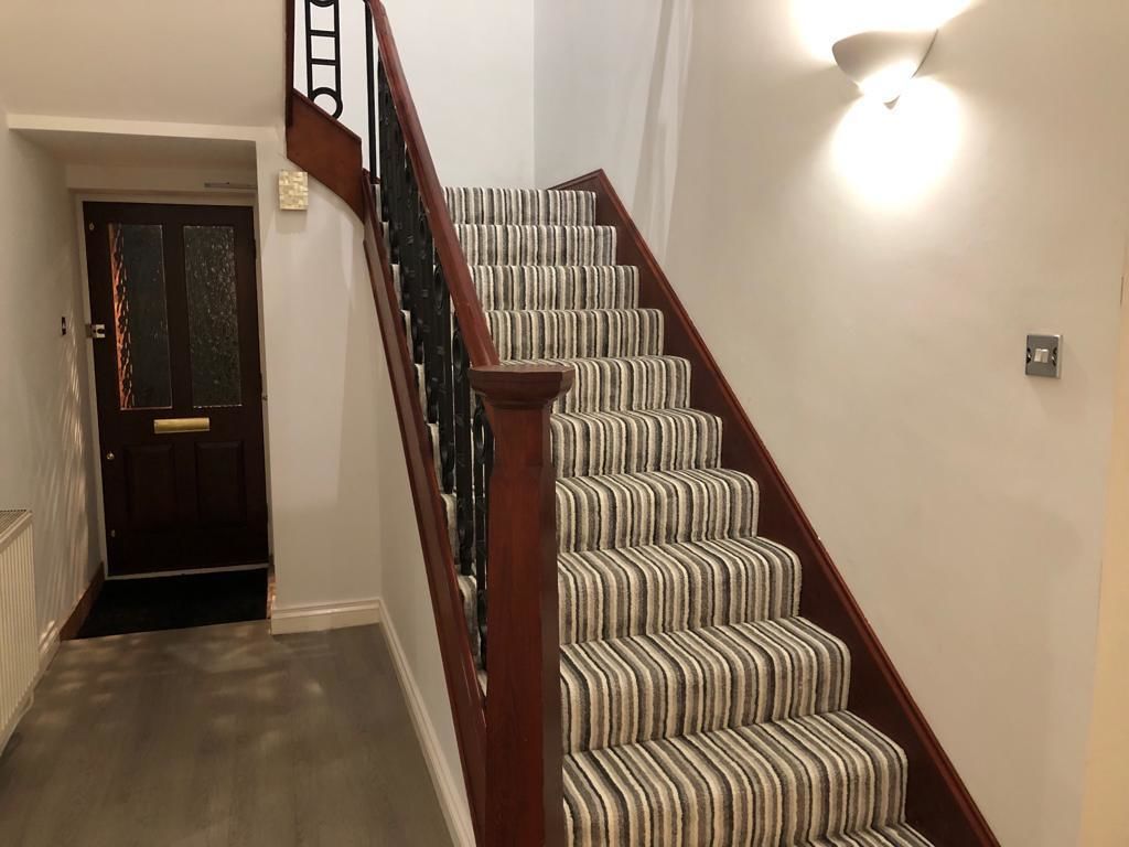Una escalera con alfombra a rayas y barandillas de madera.