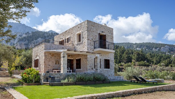A stone house with a balcony, a lawn, and a mountain backdrop. - Villa Lagoudi Stone House (Λαγουδι Ζία)