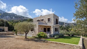 A stone house with a balcony, surrounded by a well-maintained lawn and trees. - Villa Lagoudi Stone House (Λαγουδι Ζία)