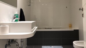 A modern bathroom with a white sink, a bathtub, and a shower. - Family-Friendly Home in Greater Beirut (Baabda)