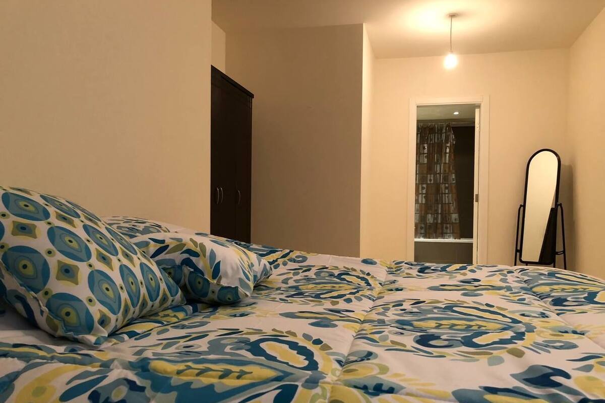 A bedroom with a bed, pillows, a wardrobe, and a mirror.