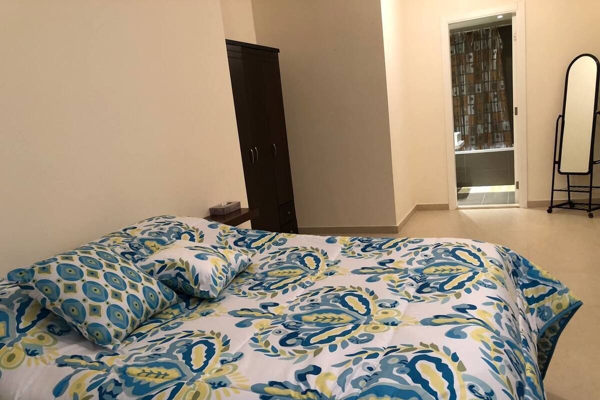 A bedroom with a bed, a wardrobe, and a mirror.