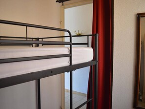 A bunk bed with a mattress, a door, and a red curtain. - Studio cabin with terrace and sea view in Banyuls-sur-Mer, 4 people (Banyuls-sur-Mer)