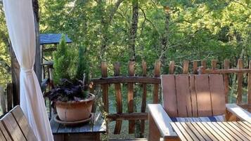 A wooden deck with a bench and table, surrounded by a wooden fence, and a 'Welcome' sign hanging above.