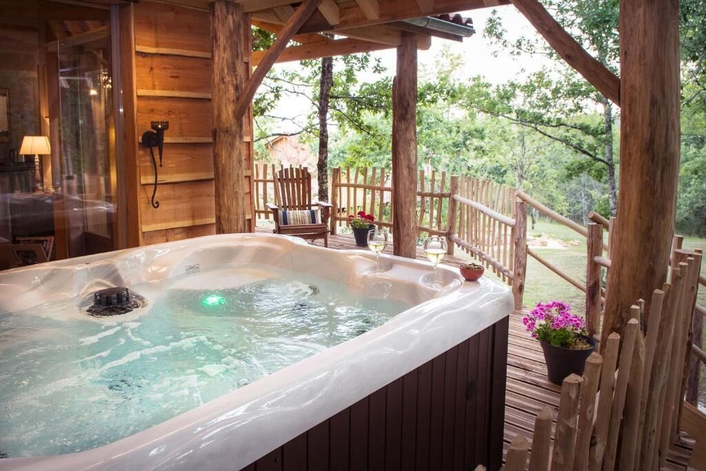 Ein Whirlpool auf einer Holzterrasse mit Holzzaun und Topfpflanzen.
