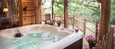 A hot tub on a wooden deck with a wooden fence and potted plants.