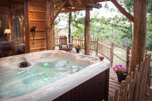Un bain à remous sur une terrasse en bois, avec une clôture en bois et des plantes en pot.
