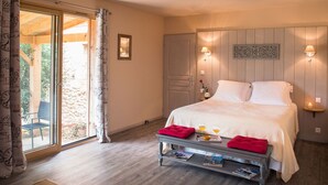 Un dormitorio con cama, lámparas de noche, una mesita de noche con un cojín rojo, una ventana con cortinas y una puerta.