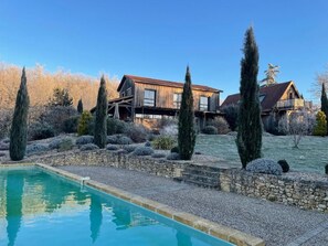 Un área de piscina con una casa de madera al fondo.
