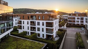 Un complexe d’appartements moderne composé de plusieurs immeubles, doté d’un parking et offrant une vue sur le coucher de soleil.