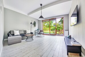 Un salon moderne avec un canapé gris, une table basse ronde et un banc en bois.