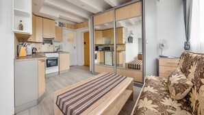 Un apartamento moderno con kitchenette, comedor y sala de estar con sofá y banca.