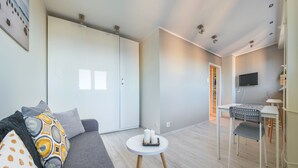 Una sala de estar moderna con un sofá gris, una mesita redonda con velas y un televisor montado en la pared.