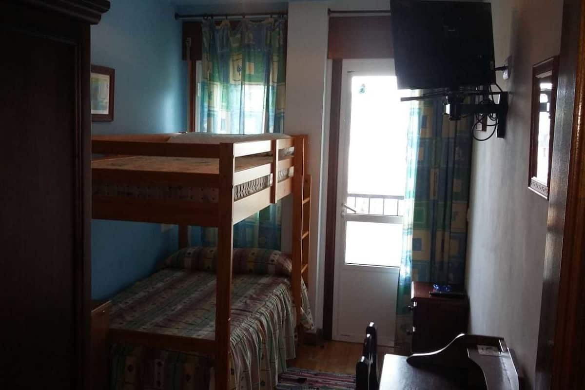 Quarto com beliches, televisão e porta que dá para o exterior.