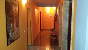 Un pasillo de hotel con un cartel a la izquierda, una planta en maceta en el centro y una puerta a la derecha.