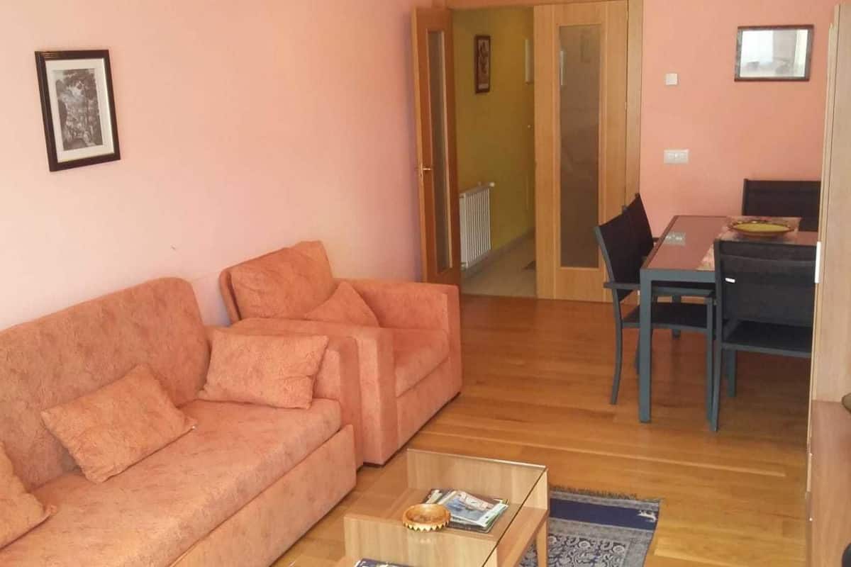 Uma sala de estar com sofá, mesa de centro e área de jantar com mesa e cadeiras.