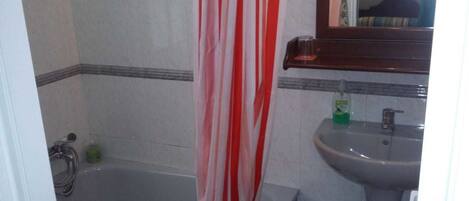 Une salle de bain avec une baignoire, un lavabo et un miroir.