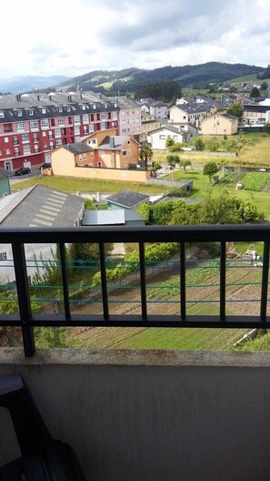 A residential area with houses, a green field, and a hilly landscape in the background. - Hospedaxe Carragal (Ribadeo)