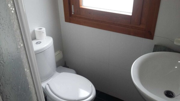 A small bathroom with a toilet, a sink, and a window above the toilet. - Hospedaxe Carragal (Ribadeo)