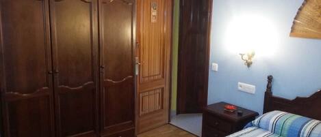 A bedroom with a bed, a nightstand, a wardrobe, and a door.