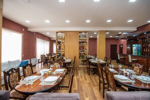 A dining area with wooden tables and chairs, a wine rack, and a bar area.