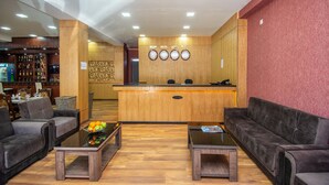 A hotel lobby with a reception desk, two sofas, a coffee table with fruit, and a bar area with liquor bottles. - Penta Tbilisi (Tbilisi)