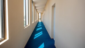 A long, narrow hallway with a blue carpet and large windows on one side. - Penta Tbilisi (Tbilisi)